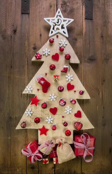 Decoración: árbol de navidad tallado a mano con miniaturas rojas . — Foto de Stock