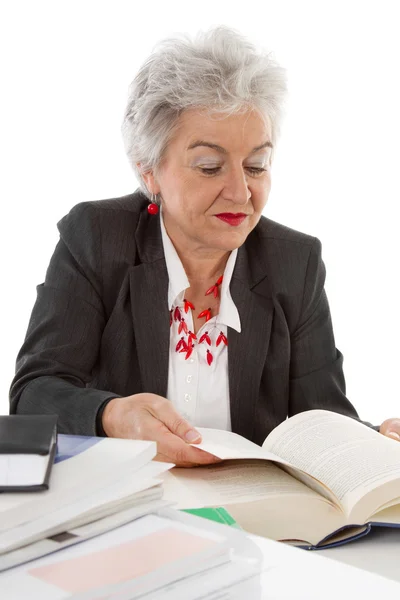 Starsza kobieta biznesu, siedząc przy biurku, czytanie w książce. koncepcja — Zdjęcie stockowe