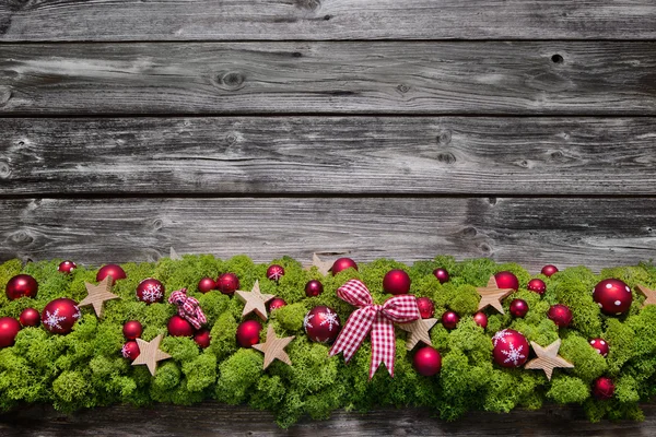 Houten Kerstmis achtergrond met groene moos en rode ballen. — Stockfoto