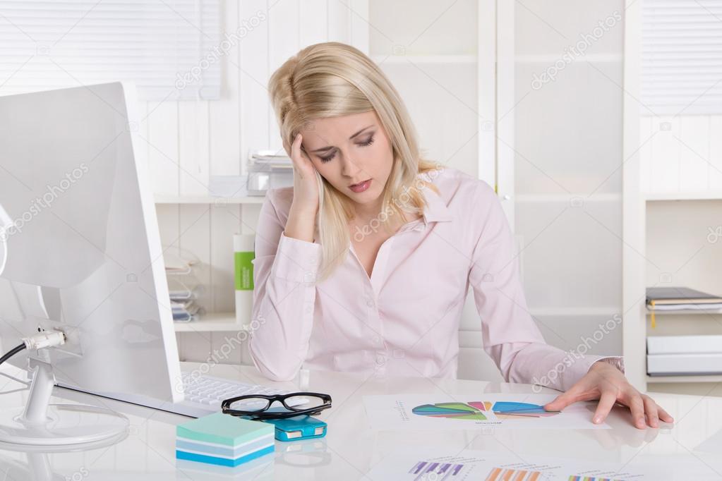 Depressed and frustrated young businesswoman sitting at desk wit