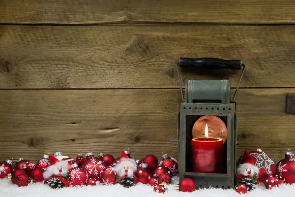 Ξύλινο χριστουγεννιάτικο φόντο με κόκκινο κερί σε ένα latern και το χιόνι — Φωτογραφία Αρχείου