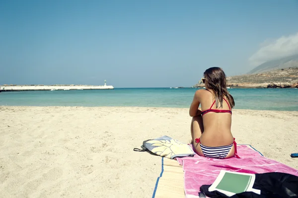 Mujer joven sentada en una hermosa playa — Foto de Stock