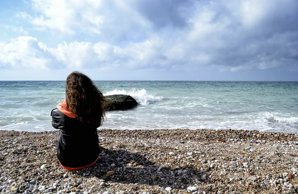 Sahilde oturan genç kız — Stok fotoğraf