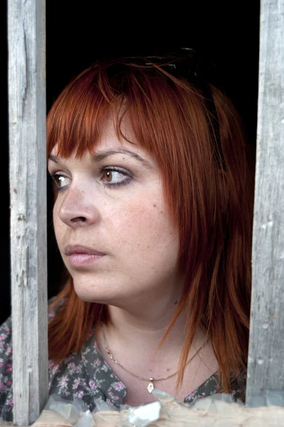 Женщина смотрит через затвор окна — стоковое фото