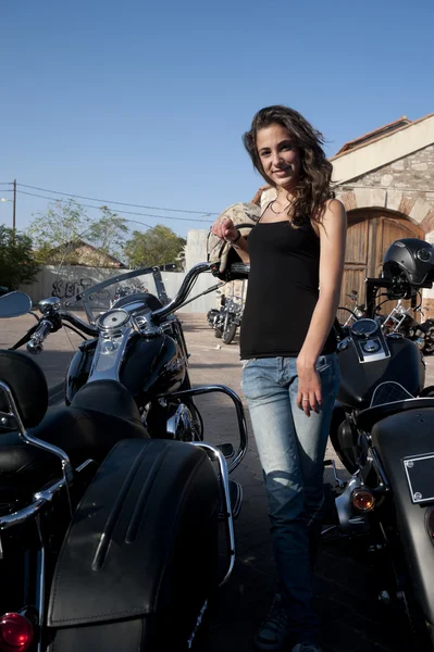 Young female stands by parked motorcycles — Stock Photo, Image