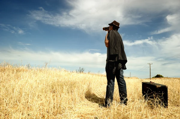 Uomo con binocolo in un campo — Foto Stock