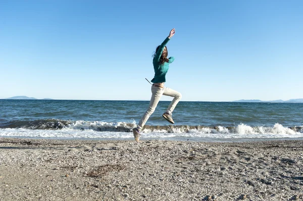 Vrolijke jonge vrouw spelen op het strand — Stockfoto