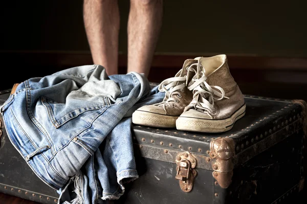 Pair of jeans and sneakers on suitcase — Stock Photo, Image