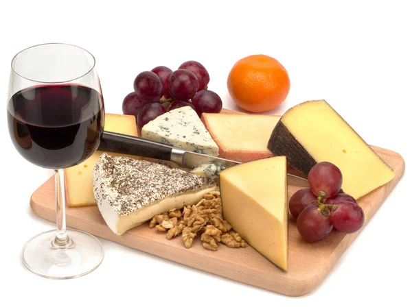 Egy pohár vörösbor és egy fából készült tábla sajttal, dióval, szőlővel. Jogdíjmentes Stock Képek