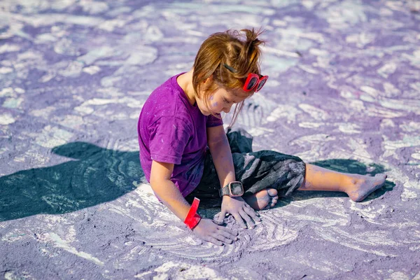 stock image a little, cheerful girl at the Holi festival, in a purple T-shirt, stained with lilac paint