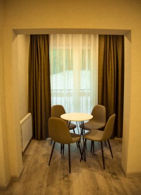 Çevre dostu mobilyalar, yuvarlak masa ve kahverengi sandalyeler, otel odasının şık iç kısmında.