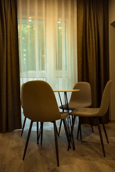 Çevre dostu mobilyalar, yuvarlak masa ve kahverengi sandalyeler, otel odasının şık iç kısmında.