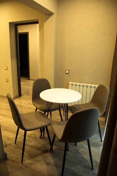 Çevre dostu mobilyalar, yuvarlak masa ve kahverengi sandalyeler, otel odasının şık iç kısmında.