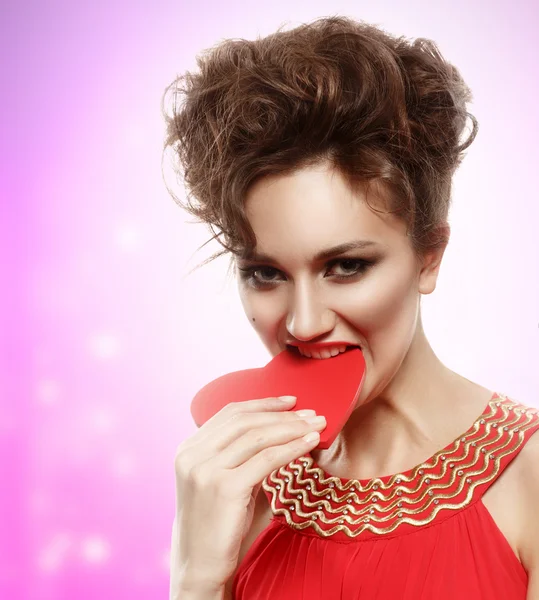 Girl in red dress eats heart. Concept of Valentine's Day — Stock Photo, Image