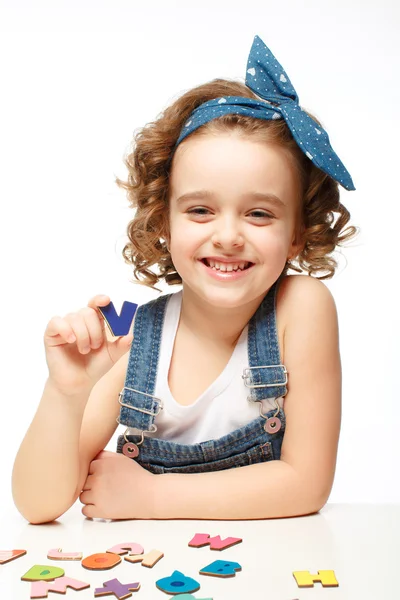 Little girl playing in the alphabet. Shows the letter V. — Stock Photo, Image