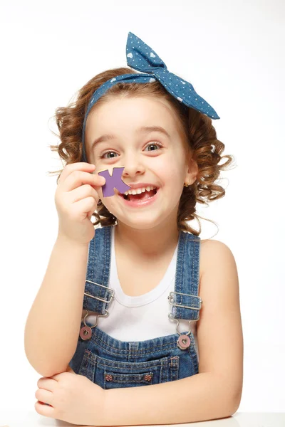 Uma menina a brincar no alfabeto. Mostra a carta. — Fotografia de Stock