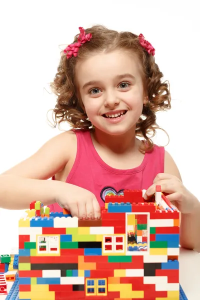 Small girl builds a house from plastic blocks — Stock Photo, Image