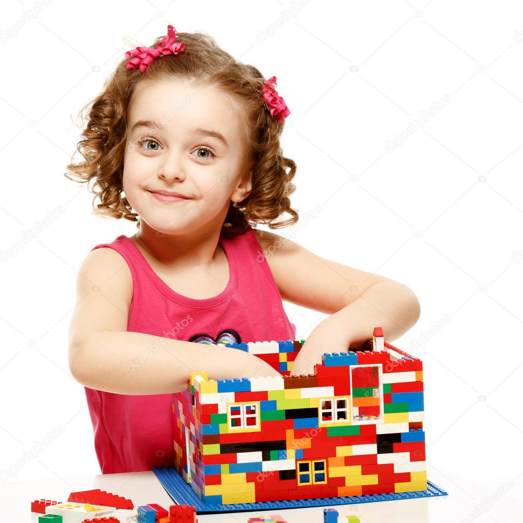 Small girl builds a house from plastic blocks