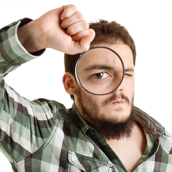 Homem de camisa verde olhando através de uma lupa . — Fotografia de Stock