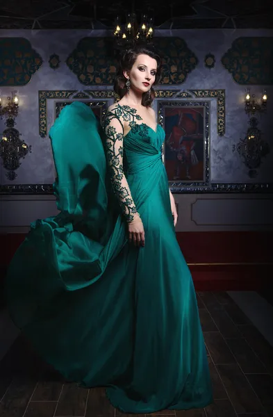 Belle femme dans une robe longue verte sur un fond de richesse — Photo