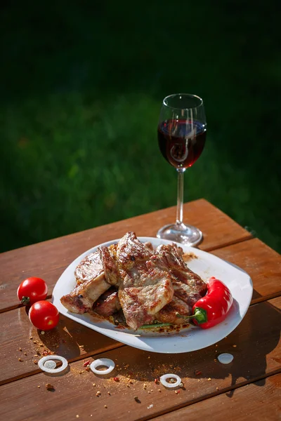 Bifes de porco grelhados em uma mesa de madeira com um copo de vinho — Fotografia de Stock
