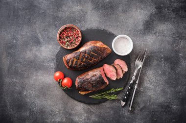 Duck breast on a slate board, grilled with peppers and cherry tomatoes