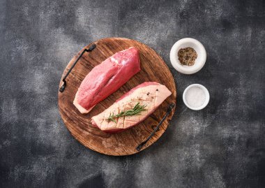 Çiğ ördek göğsü, otlar ve baharatlarla koyu beton bir arka planda. Pişirmeye hazır çiğ et.