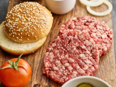 The raw ingredients for the homemade burger. Burger patties. Raw mince meat cutlet, ground beef and pork with bun. Grey background. 