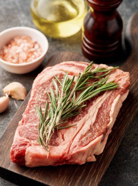 Raw ribeye steak on a wooden board. Preparing raw beef steak for barbecue grill