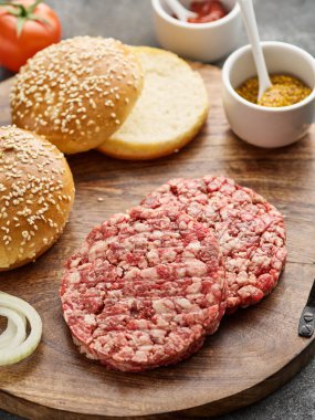 The raw ingredients for the homemade burger. Burger patties. Raw mince meat cutlet, ground beef and pork with bun. Grey background. 