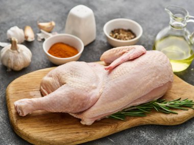 Half raw chicken, Ingredients for cooking, garlic, vegetables on wooden rustic board, uncooked chicken