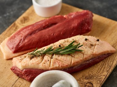Raw duck Breasts with skin set, with herbs and ingredients, on wooden board, close up