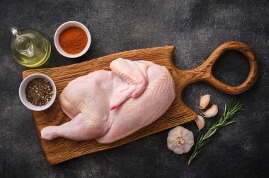 Half raw chicken, Ingredients for cooking, garlic, vegetables on wooden rustic board, uncooked chicken, top view