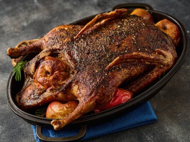 Roast goose stuffed with baked apples in a skillet on a grey background, festive christmas recipe. 