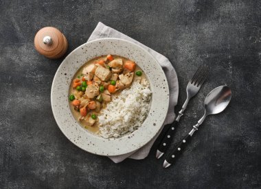 Tender chicken fillet in a creamy mushroom sauce with rice and green peas. Chicken stew with vegetables and mushroom cream sauce. 