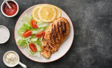 Fried chicken breast. Grilled chicken breast with vegetable salad and lemon. Top view, flat lay.