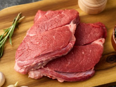 Two Raw Entrecote with garlic and rosemary, on a wooden board. close-up