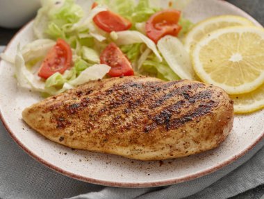 Fried chicken breast. Grilled chicken breast with vegetable salad and lemon. Close up.