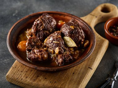 Stewed pork cheeks with vegetables, on a grey background. Spanish or German food. clipart