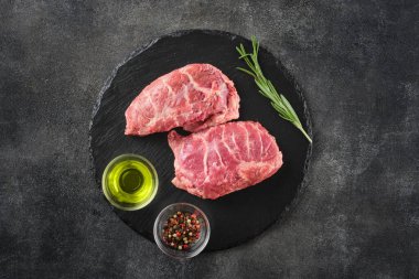Koyu gri bir yüzeye biberiye ve baharatla çiğ domuz yanağı. Üst Manzara. Gıda arkaplanı.