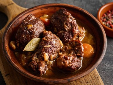 Gri arkaplanlı, sebzeli domuz eti yanakları. İspanyol ya da Alman yemekleri.