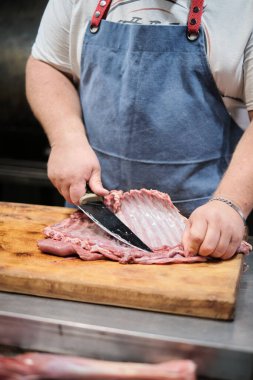 Kasap pirzolaları temizler. Et sigara ya da barbekü için hazırlanıyor.