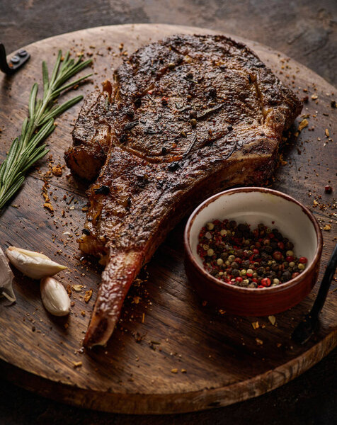 Мраморный бифштекс томагавк сухой выдержки на деревянной доске со специями. Крупный план. Сочный вкусный рибай или томагавк стейк