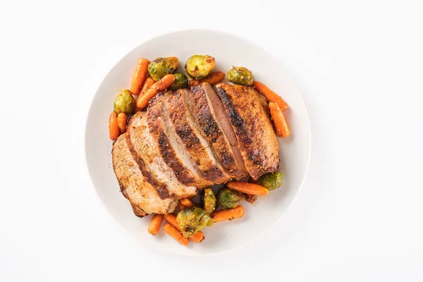 Roast pork loin with herbs and vegetables on white background. Sliced Pork Meat.