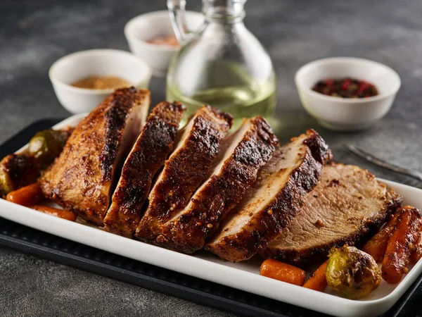 Roasted pork Loin with carrot and broccoli. Sliced Pork Meat. Grey background. Close-up.