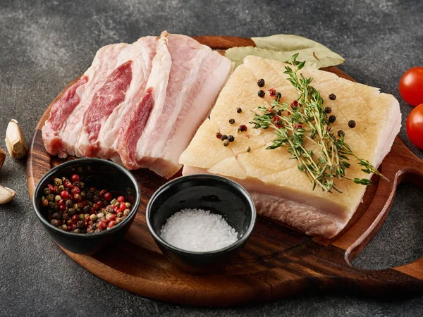 Raw Pork belly. Fresh pork belly block with spices on wooden board prepared for BBQ , close-up.