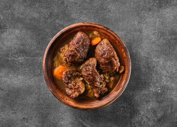 Traditional German braised pork cheeks in brown sauce with carrot as closeup