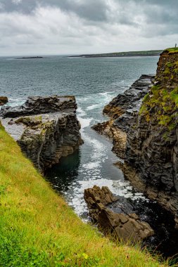 Water inlet on a rocky cliff on the coastal walk route from Doolin to the Cliffs of Moher, rainy day with a gray sky with heavy clouds in County Clare, Ireland. Geosites and Geopark, Wild Atlantic Way