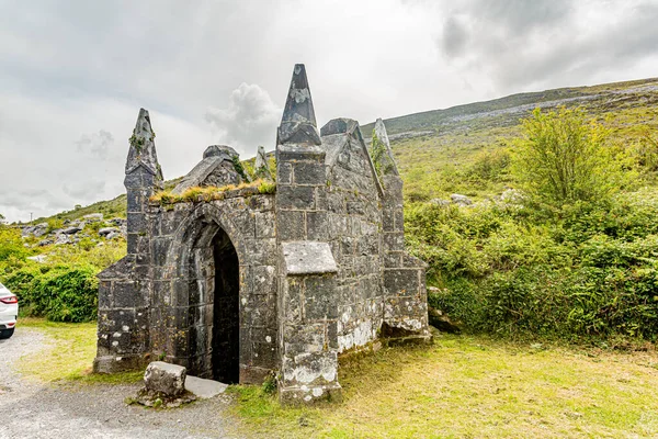 Medieval ruin with a water source in the middle of the meadow in the Burren, geosite and geopark, Wild Atlantic Way, cloudy spring day in County Clare in Ireland