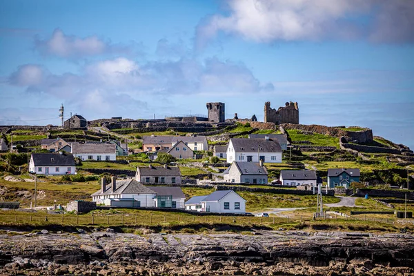 Beautiful view of the ruined castle of the 15th century in a prehistoric stone fort and its limestone fences on the Inis Oirr island seen from a boat, wonderful sunny day in the Aran Islands, Ireland